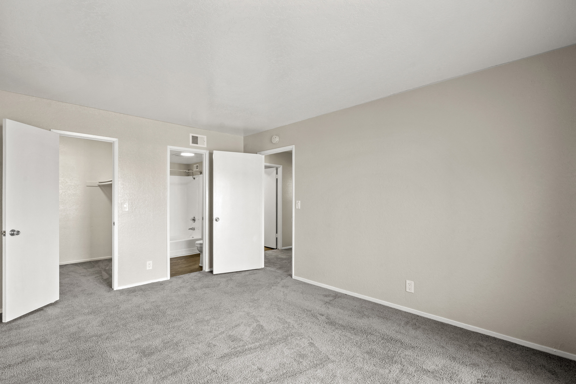 the living room of an apartment with carpet and white walls